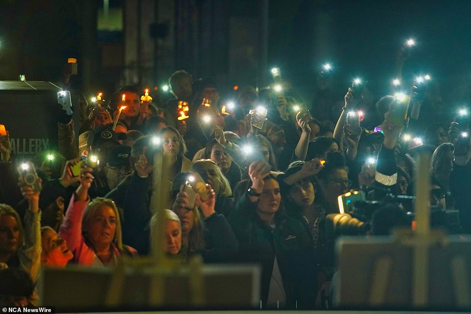 Members of the community are seen shining their telephone flashlights in solidarity.