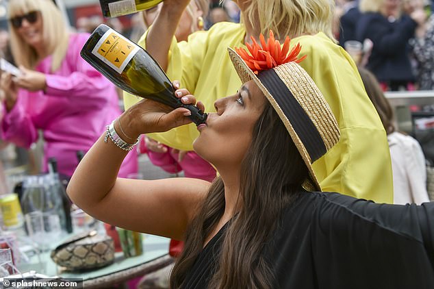 A woman is pictured drinking a bottle of champagne at today's event in Liverpool.