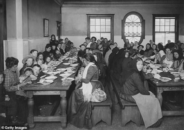 Pictured: A group of women and children eating at Ellis Island, the long wooden tables pushed together to accommodate as many people as possible in this dining room.