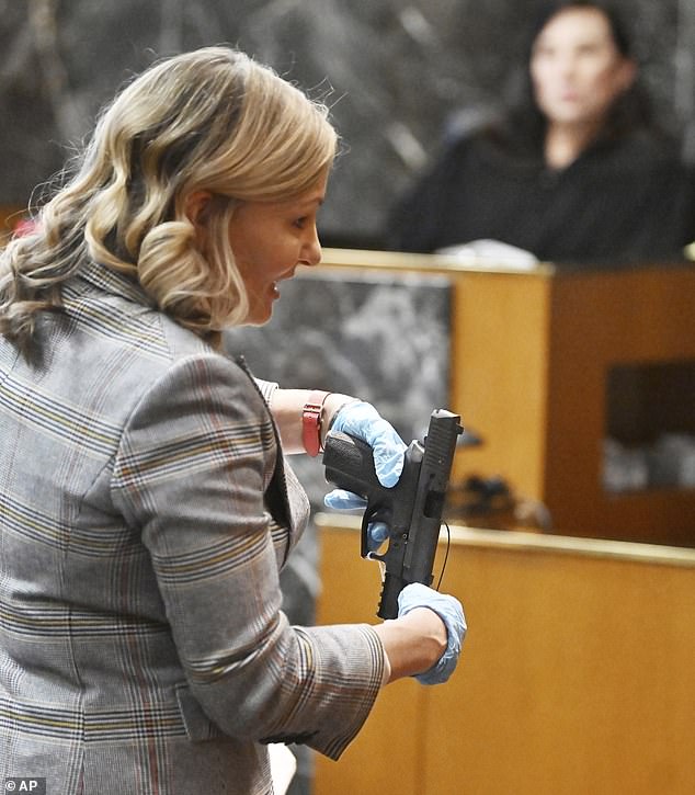 Oakland County Prosecutor Karen McDonald holds the murder weapon at James' trial, as the jury heard how he purchased the firearm for his son despite his disruptive behavior.