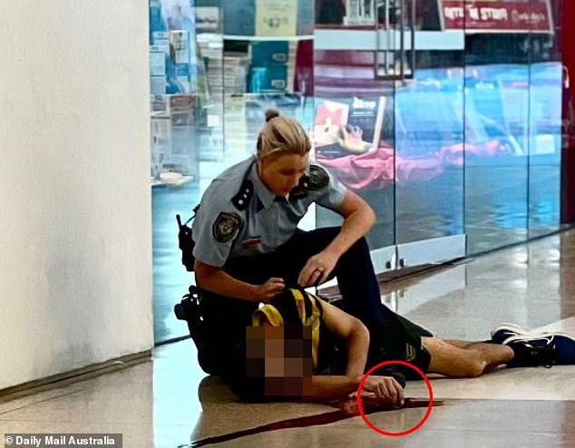 The police officer (pictured holding the man he stabbed) has been hailed as a hero by Prime Minister Anthony Albanese.