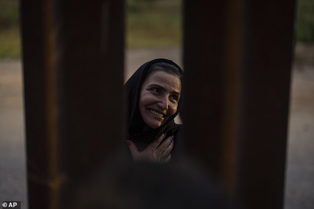 Georgian migrant Nani smiles as she thanks an American volunteer, speaking between gaps in one of the border walls separating Tijuana, Mexico, and San Diego, as she waits to apply for asylum in the United States on Friday.