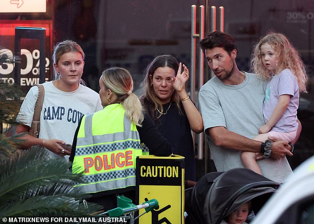 Six innocent shoppers, including the mother of an injured nine-month-old baby, died in the horrific knife attack on Saturday afternoon (pictured, witnesses speaking to an officer at the scene)