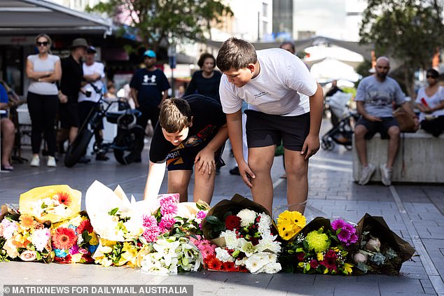 Children are seen laying flowers in tribute to the victims and people fighting for life in the hospital.