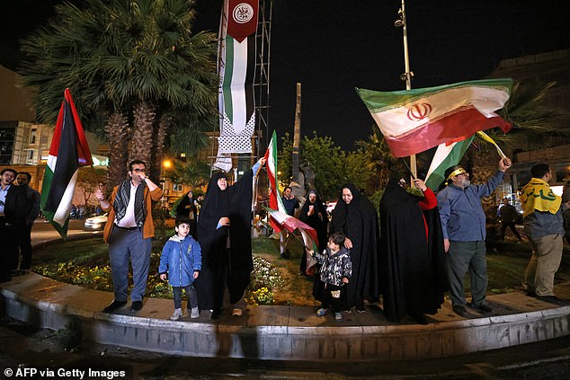 Protesters wave the Iranian flag and Palestinian flags as they gather in Palestine Square in Tehran on April 14, 2024.