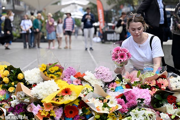 A woman places flowers at a makeshift shrine formed on the outskirts of Bondi Junction Westfield following Saturday's mass stabbing.