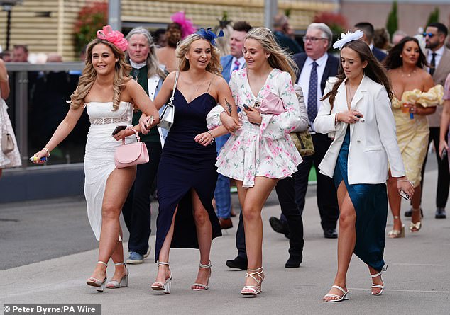 A group of smiling friends at the Merseyside racecourse in shades of white.