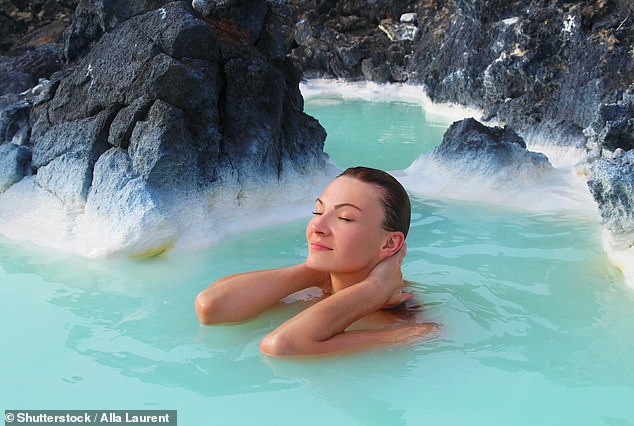 A woman with her eyes closed relaxes and enjoys the spa in the hot springs of the Blue Lagoon in Iceland