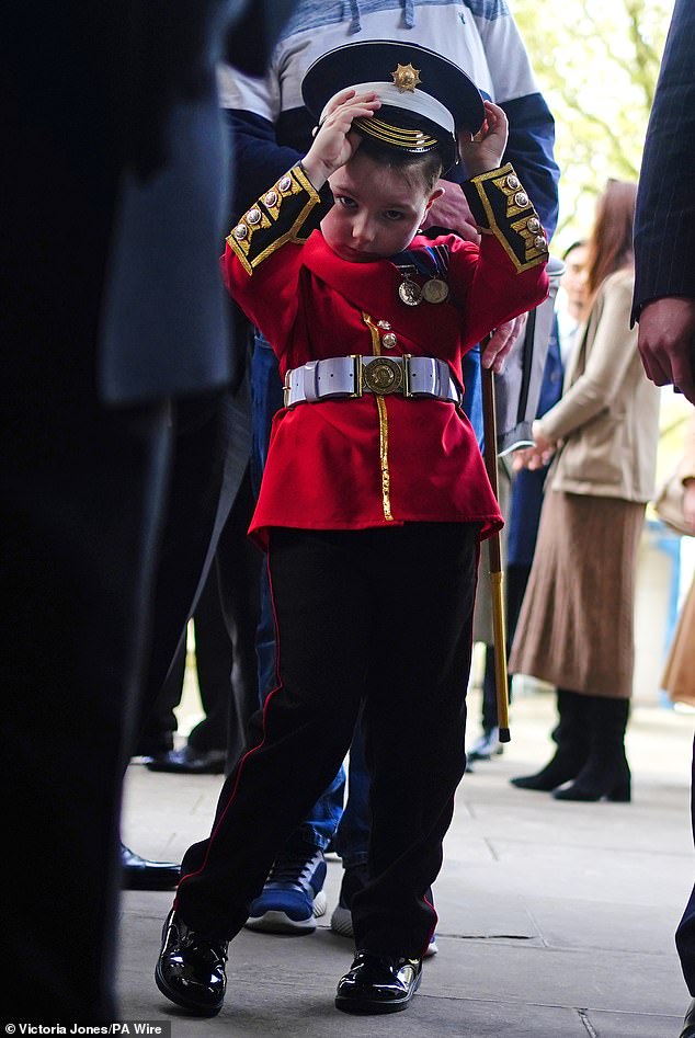 A boy in a replica uniform joins members of the Scots Guards as they gather before the Black Sunday Parade, in the chapel of the Guards Museum at Wellington Barracks.