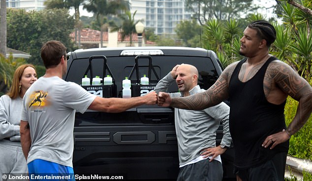 A member of the USC Trojans is seen fist bumping Aaron Rodgers after their workout.