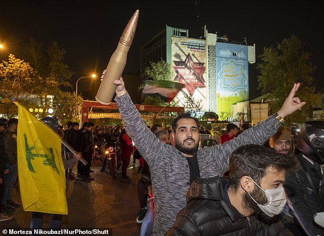 An Iranian man holds a scale model of a cannon projectile during a celebration in support of Iran's IRGC UAV and missile strike against Israel.