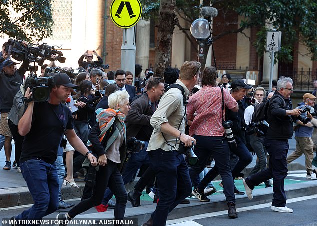 Bruce Lehrmann remained impassive and silent as he was followed down the street and a cameraman was seen falling to the pavement amid the chaos (pictured).