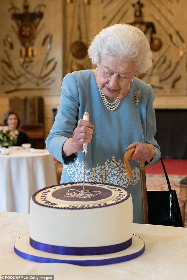 Elizabeth II cuts a cake to celebrate the start of the Platinum Jubilee during a reception in the ballroom at Sandringham House (pictured)