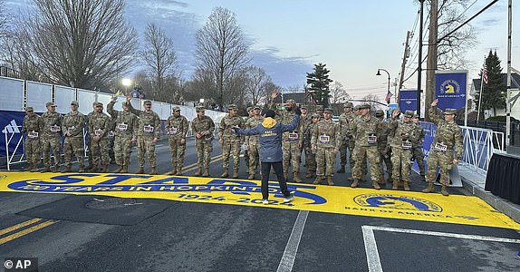 Boston Marathon race director Dave McGillivray sends a group of Massachusetts National Guard members across the starting line in Hopkinton on Monday, April 15, 2024, to begin the marathon. The starting line was painted in honor of the town that has hosted the marathon for the last century. It is the 128th edition of the oldest and most prestigious annual marathon in the world. (AP Photo/Jennifer McDermott)