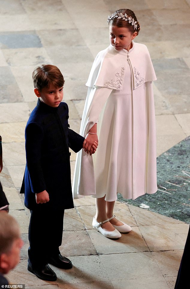 Pictured: Princess Charlotte and Prince Louis hold hands as they arrive at the coronation of King Charles and Queen Camilla in May 2023.