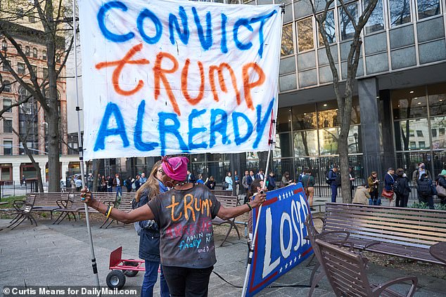 Anti-Trump protesters with large signs stand outside the Manhattan Criminal Court at 100 Center Street in New York City on Monday awaiting the former president's arrival.