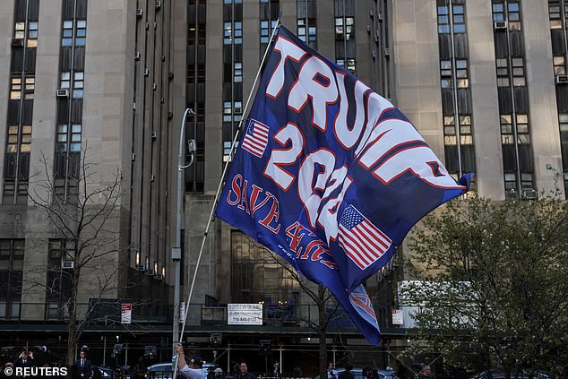 A Trump supporter holds a flag supporting the former president's re-election outside Manhattan Criminal Court on Monday before his arrival.