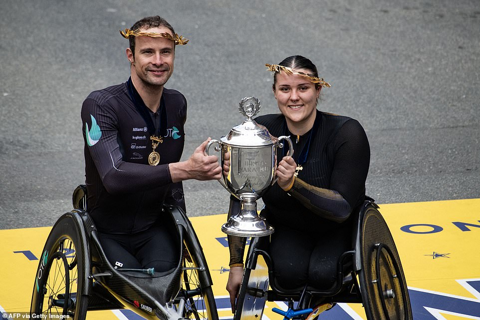 Swiss athlete Marcel Hug and English athlete Eden Rainbow Cooper hold a trophy after finishing first in the men's and women's professional wheelchair category