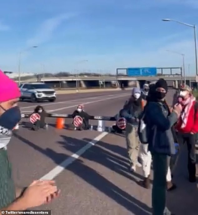 Protesters are seen sitting on the sidewalk, united together as they block the entrance to the airport.