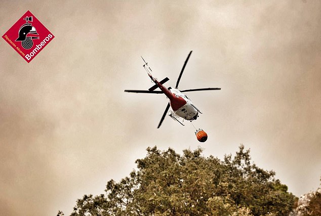 A helicopter is seen working to put out fires in eastern Spain on Monday