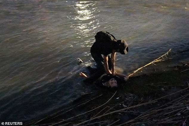 A man tries to revive an unconscious man from Mexico who lies on the bank of the Rio Grande near Eagle Pass.