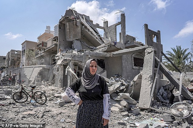 A woman stands in the rubble in front of a collapsed building on the eastern side of the Maghazi camp for Palestinian refugees in the central Gaza Strip.