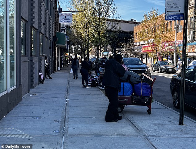 Illegal vendors are on the streets of Roosevelt Avenue and one vendor, wearing a black mask over his head, loads his wares, including speakers and electronic equipment, into a cart.