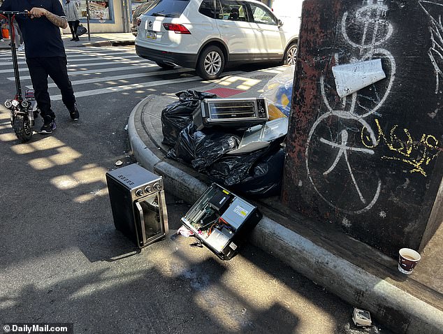 Black garbage bags, toaster ovens and electronic equipment litter the corner of Jackson Heights street.