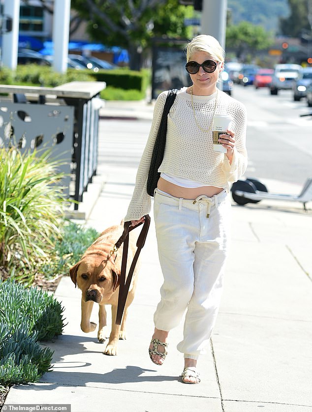 She opted for a monochrome white ensemble while rocking a pair of low-rise oversized jeans with a thick cream rope as a belt. She donned a pair of printed strappy sandals to walk her dog and get a midday pick-me-up at a coffee shop.
