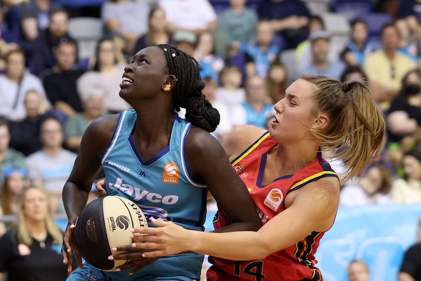 Adelaide Lightning's Isobel Borlase defends Southside Flyers' Nyadiew Puoch in the WNBL.