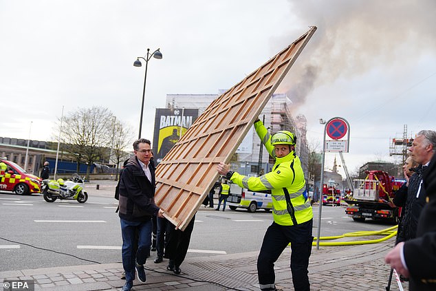Locals carry paintings and other objects as a fire burns down the former Stock Exchange (Boersen) in Copenhagen, Denmark, April 16, 2024.