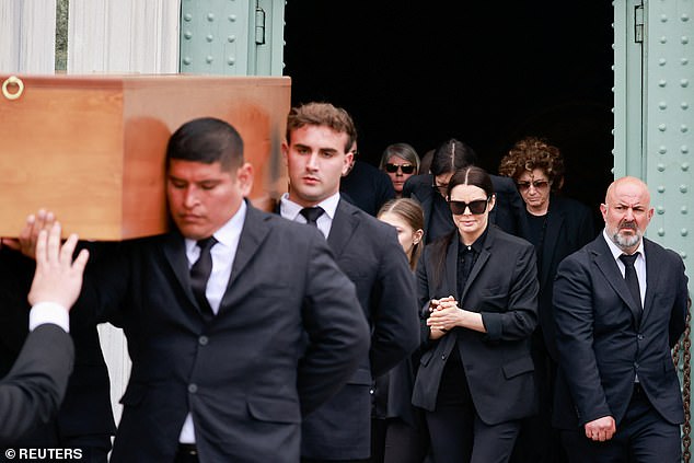 The former model is photographed looking emotional as she follows the coffin of her partner Roberto Cavalli