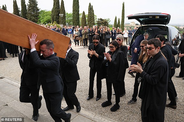 Sandra and other mourners are seen applauding as the coffin is carried into the church. Roberto died last week after a long illness