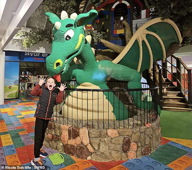 Matthew Sutcliffe at Legoland in Denmark, pictured next to a bright green Lego dragon.