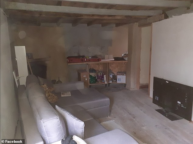 The living room, still under renovation, with a sofa, TV and some basic furniture.