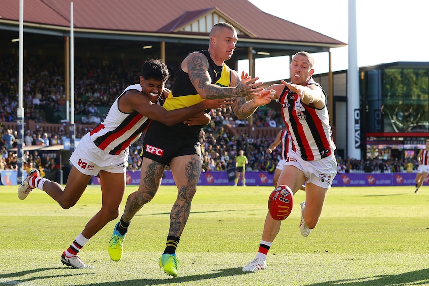 Saints' Nasiah Wanganeen-Milera and St Kilda's Callum Wilkie try to stop Richmond's Dustin Martin during an AFL match.