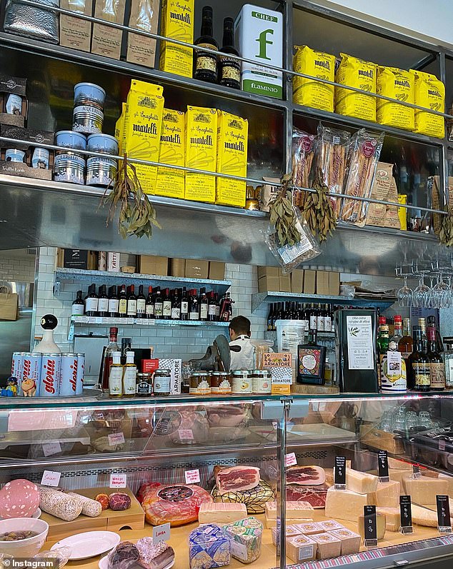 Salumeria Norcino's glass façade shows the deli counter and dining room beneath shelves of Italian food stacked with bags of Italian coffee, flour, cans of olive oil and canned tomatoes.