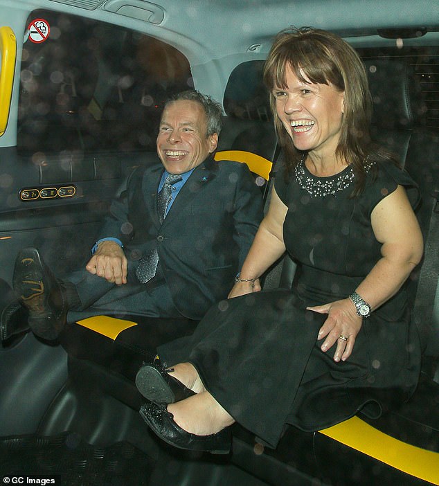 Warwick and Samantha smile and hold hands in the back of a taxi while attending the Pride of Britain Awards at the Grosvenor House Hotel in October 2014 in London.