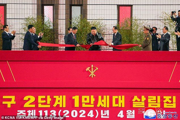 Kim was then seen wearing her favorite black leather bomber jacket as she used scissors to cut the red ribbon (pictured) while standing atop a large podium, decorated with communist red ribbons and adorned with a sickle and a golden hammer