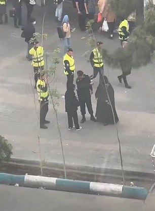 An alleged morality policeman is seen arguing harshly with a woman on the street before leading her towards a van, even though she appears to be wearing a hijab.