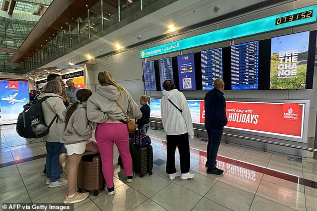 Passengers check their flight information on screens at Dubai International Airport this morning