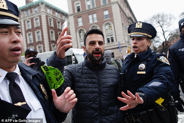 NYPD officers remove a man as pro-Palestinian protesters march outside Columbia University in New York City on April 18, 2024.