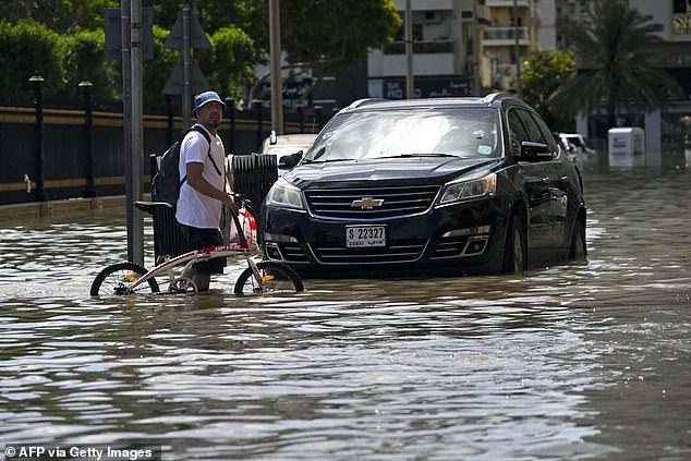A man crosses a flooded street after heavy rain in Sharjah on April 17, 2024.