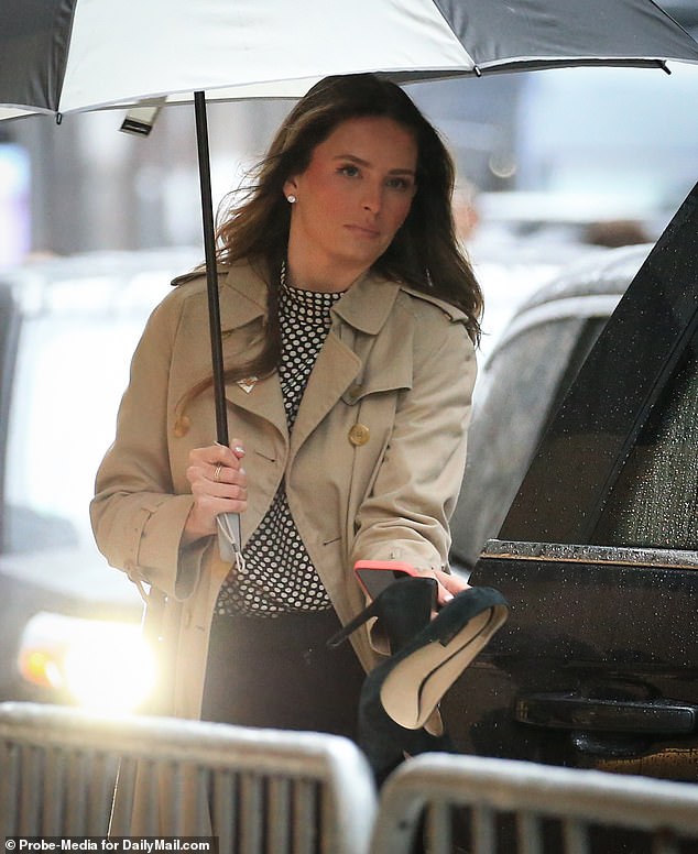 She is seen here with black suede shoes in her hand on a rainy Thursday outside the court.