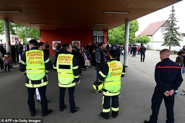 Parents pick up their children as police forces and firefighters look on at a school in the eastern French town of Souffelweyersheim after two girls were injured in a knife attack outside the school on April 18, 2024.