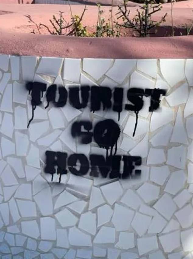 An anti-tourist message is scrawled on the side of a bollard on the island