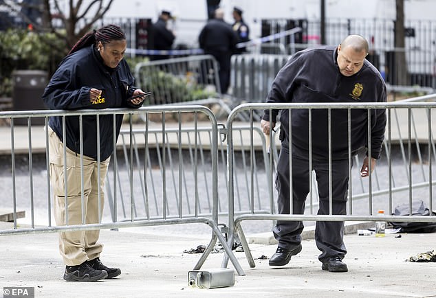 Police officers investigate a canister of flammable liquid abandoned at the scene where a man set himself on fire in Collect Pond Park, across from Manhattan Criminal Court.