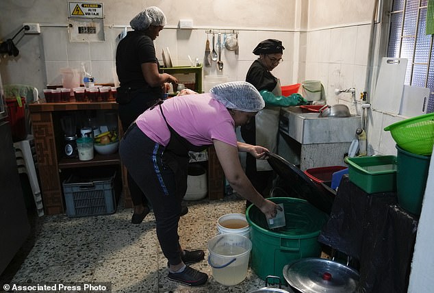 A restaurant cook draws water from a bucket as the kitchen remains open during a 24-hour water restriction in Bogotá, the capital of Colombia that is dealing with a drought.