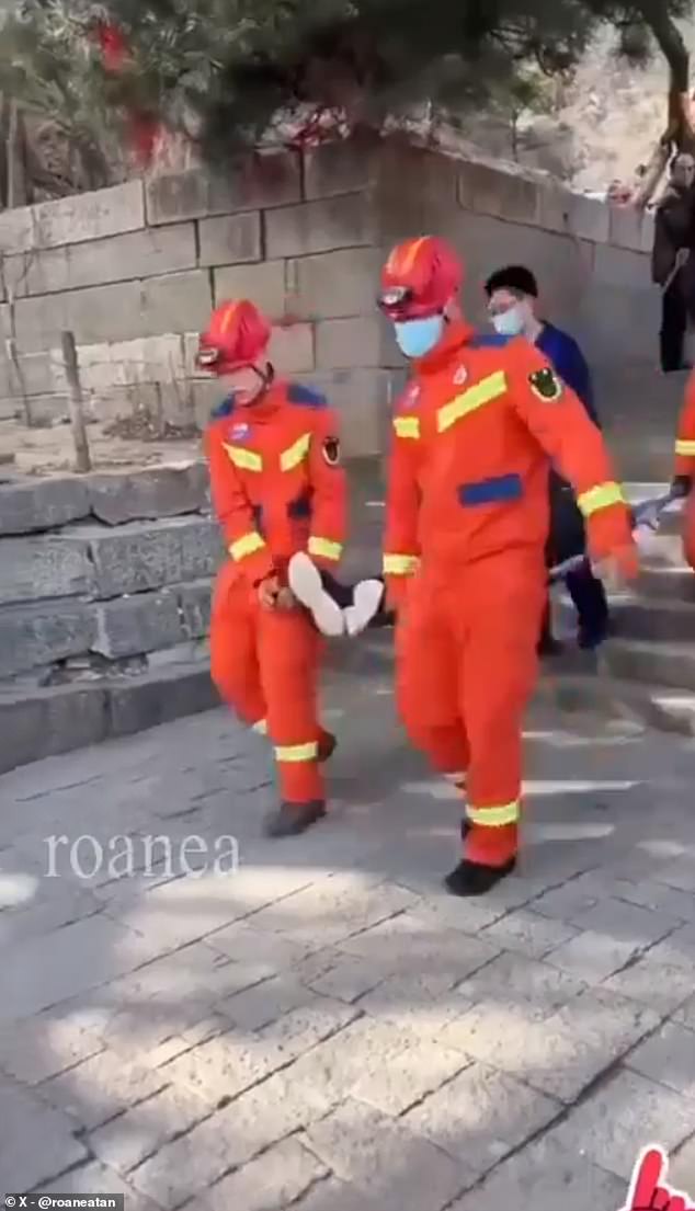 In a shocking clip, an exhausted individual is seen being carried down a series of steps on a stretcher by healthcare workers dressed in high-visibility orange jackets.