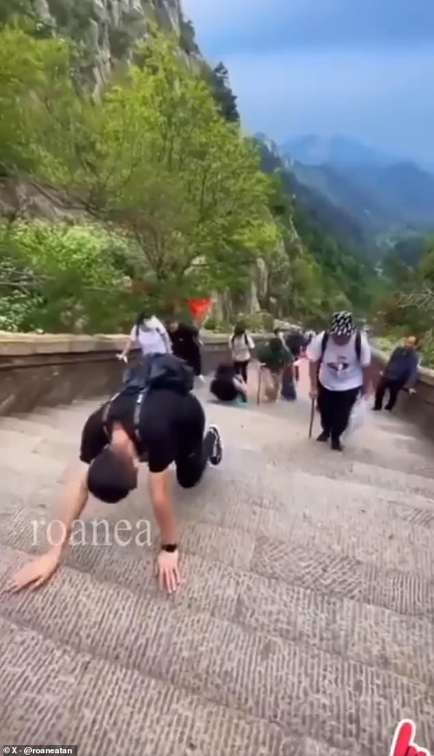 Groups of men crawl on hands and knees up steeper steps across the mountain.